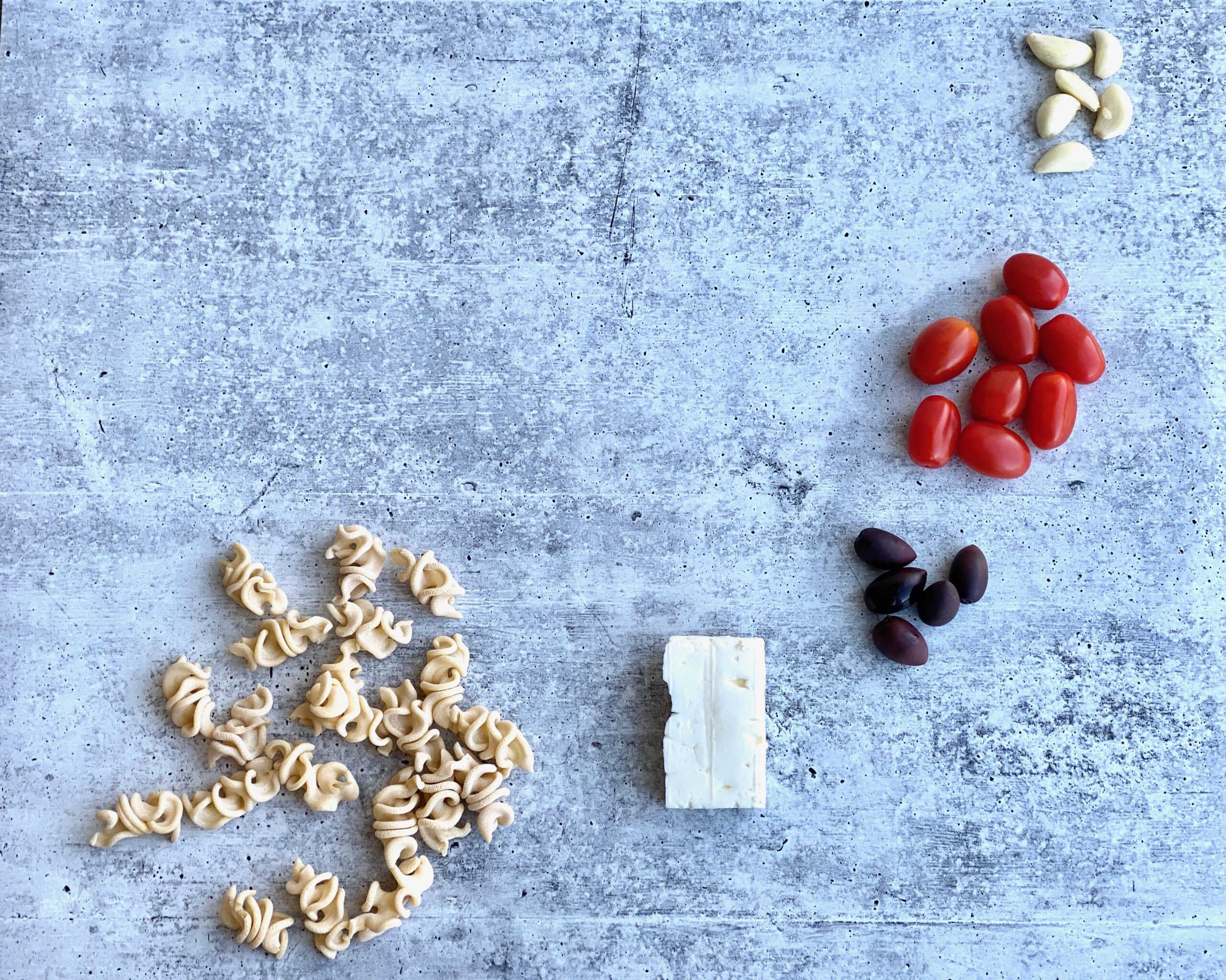 Image of ingredients - tomatoes, feta, pasta and garlic