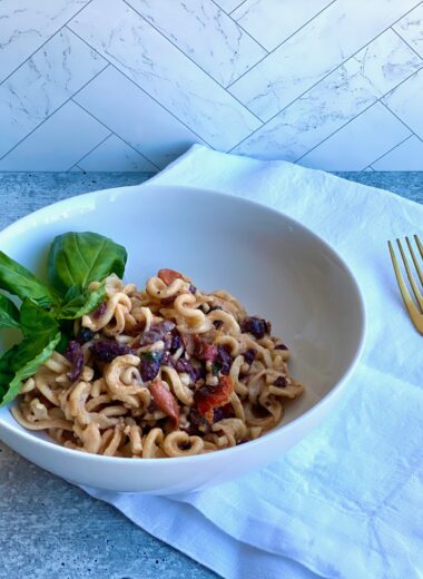 Image of a bowl of pasta with a fork and napkin next to it