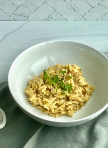 An image of a bowl of orzo with a rind of parmesan cheese and a spoon