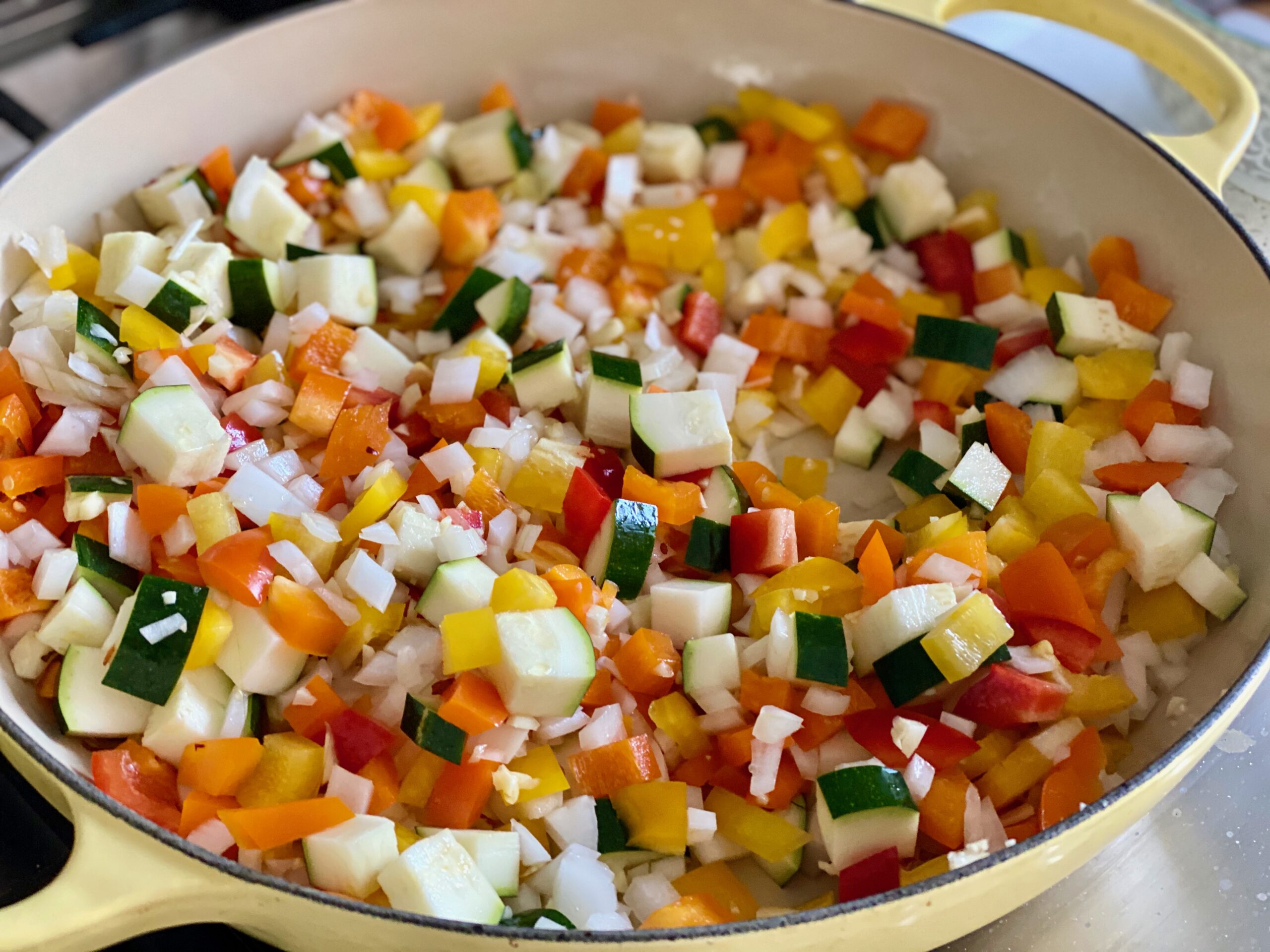 A pan of pepper, onions and zucchini cooking