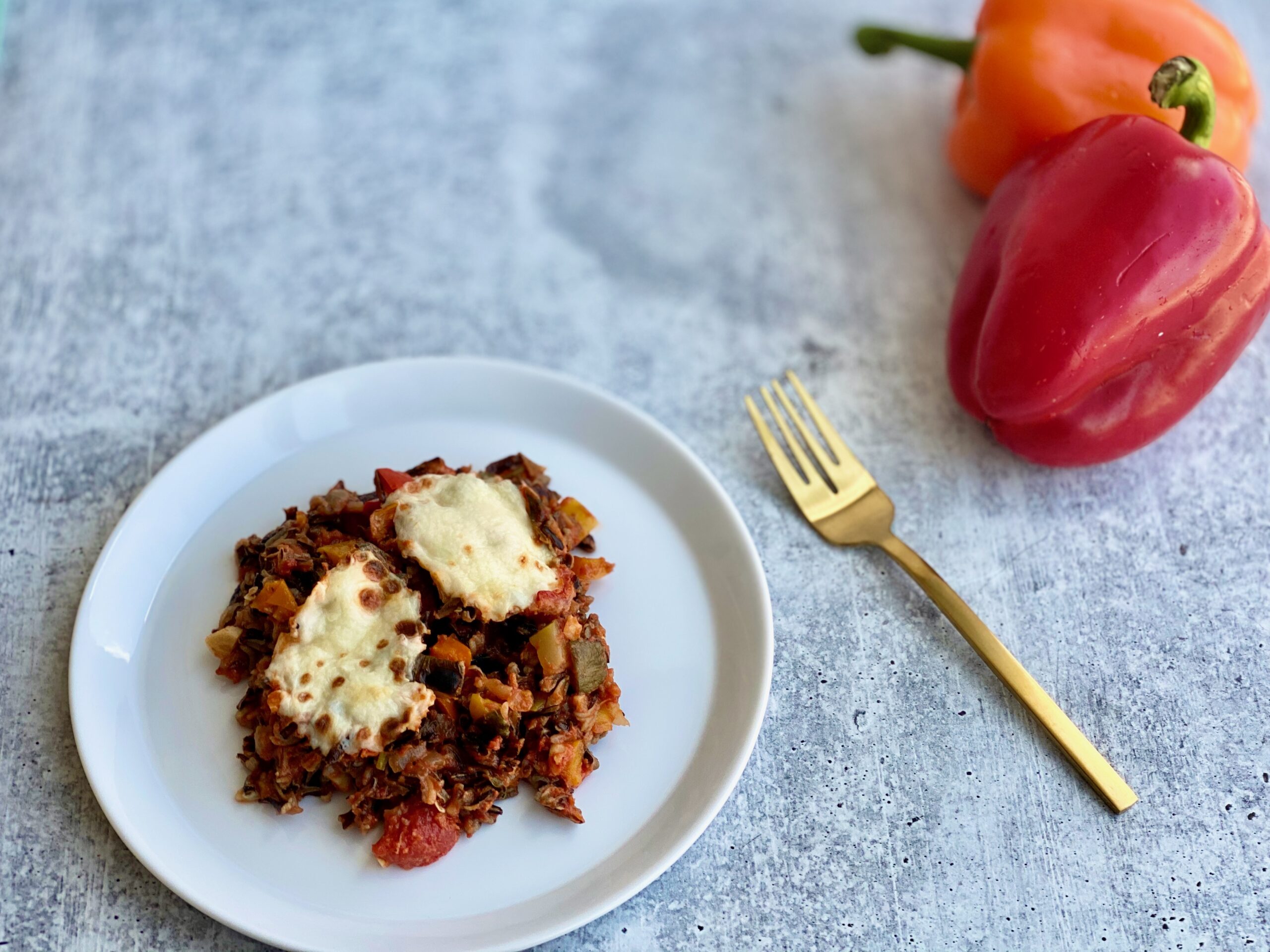 An image of a plate of stuffed peppers with bell peppers in the background