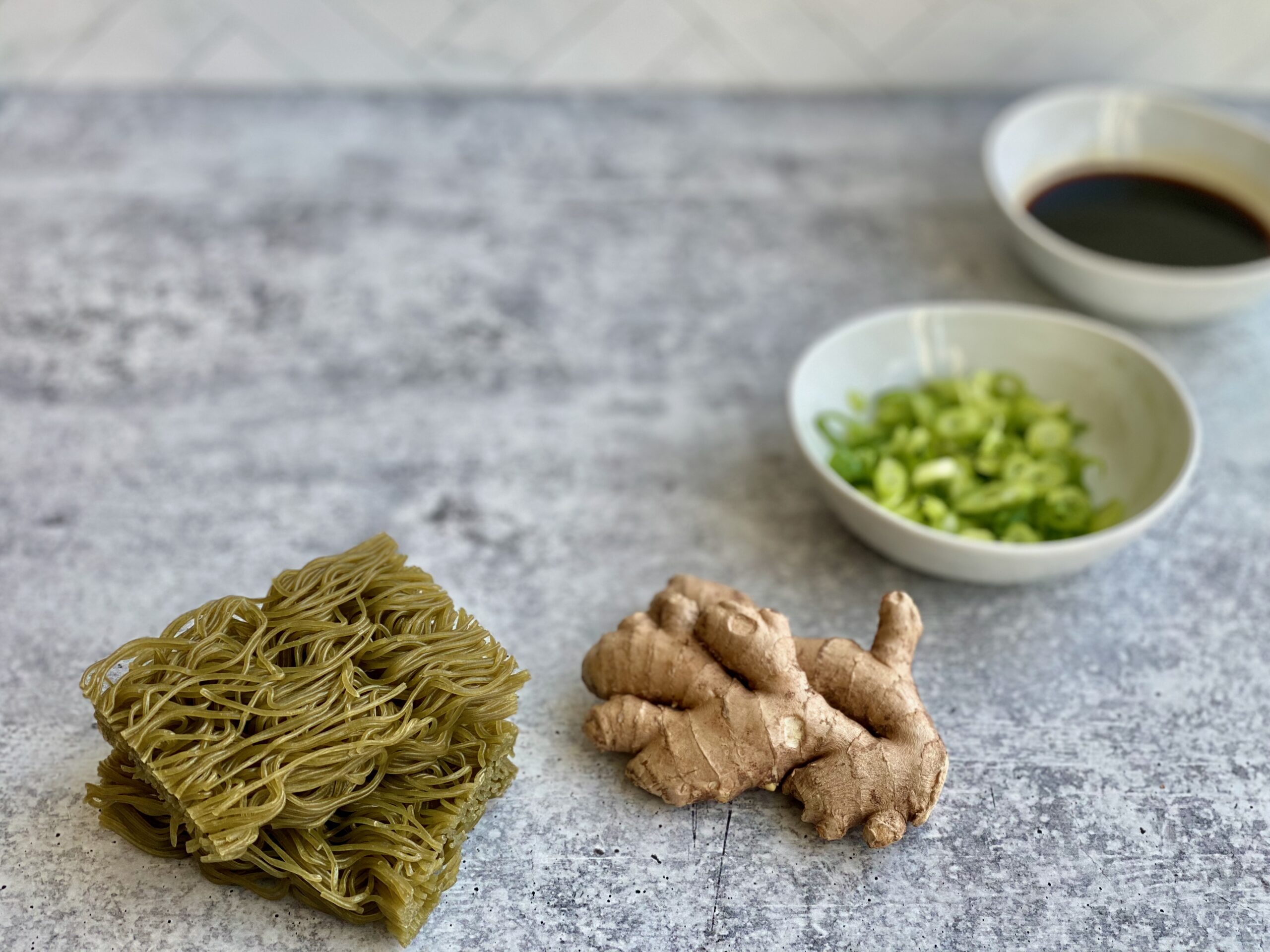 Image of ingredients to make ramen noodles including ginger, scallions and soy sauce.