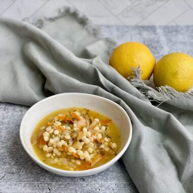 Picture of a bowl of soup with lemons in the background