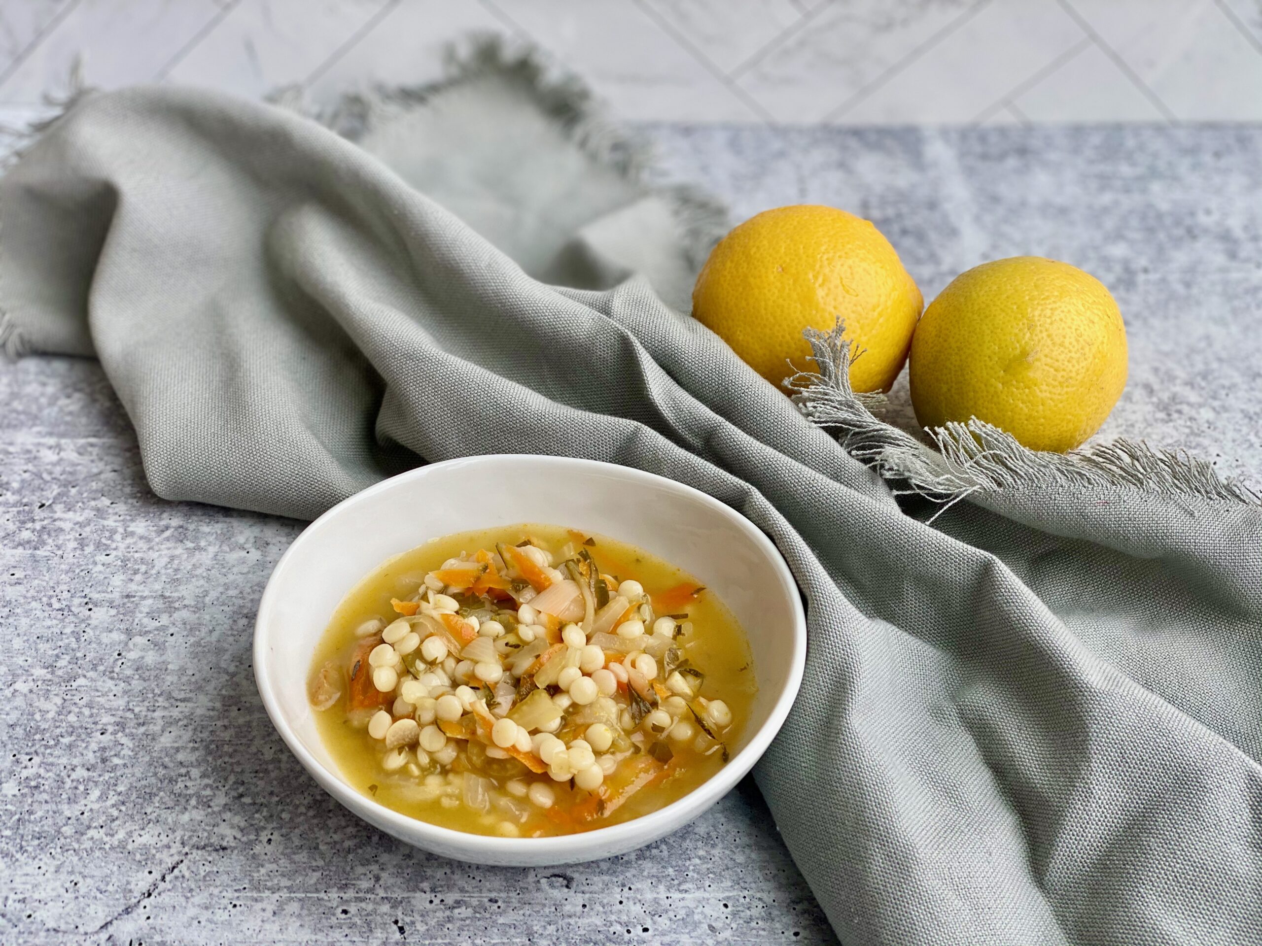 Picture of a bowl of soup with lemons in the background