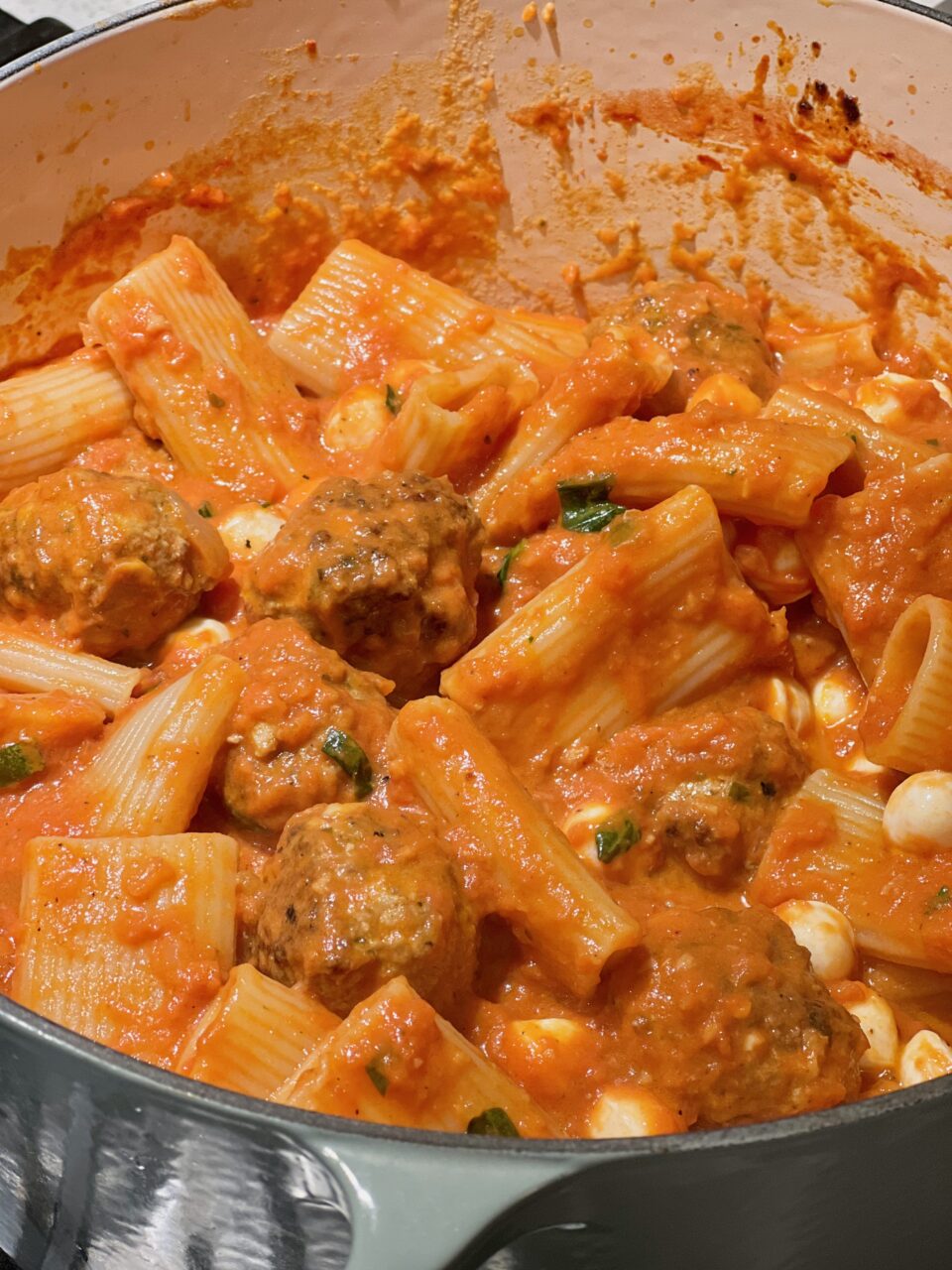 A large pot of tomato sauce cooking with meatballs