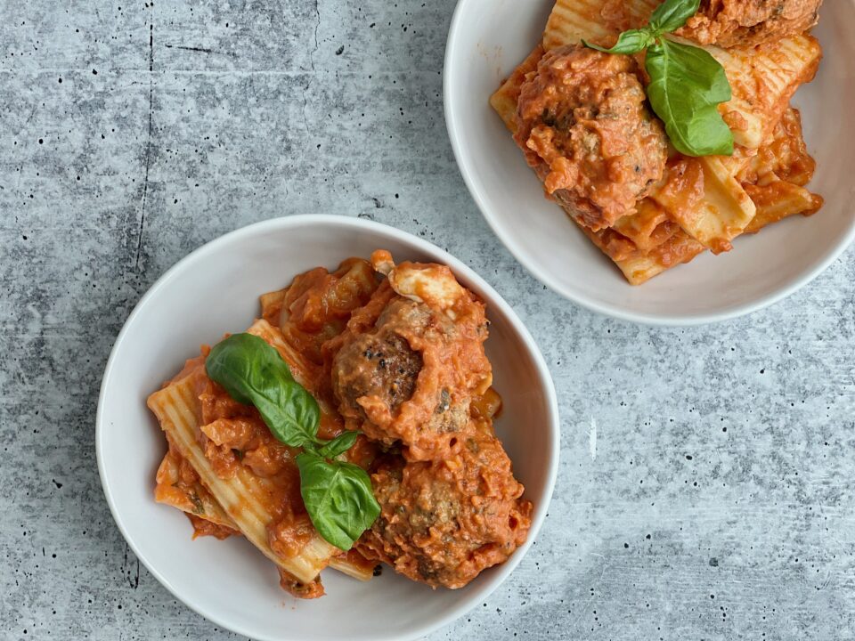 Two bowls filled with pasta and meatballs