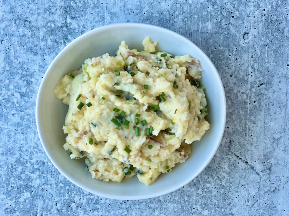 A bowl of smashed potatoes with green garlic