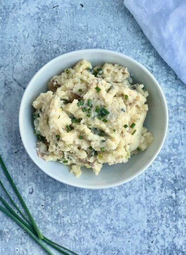 A bowl of smashed potatoes with green garlic