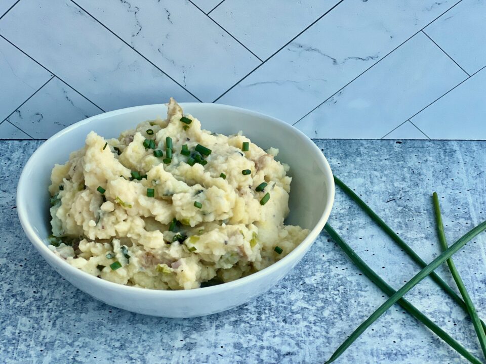A bowl of smashed potatoes with green garlic