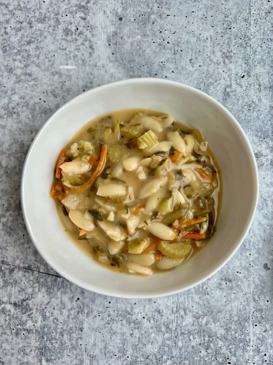 A bowl of creamy lemon orzo soup with lemons in the background