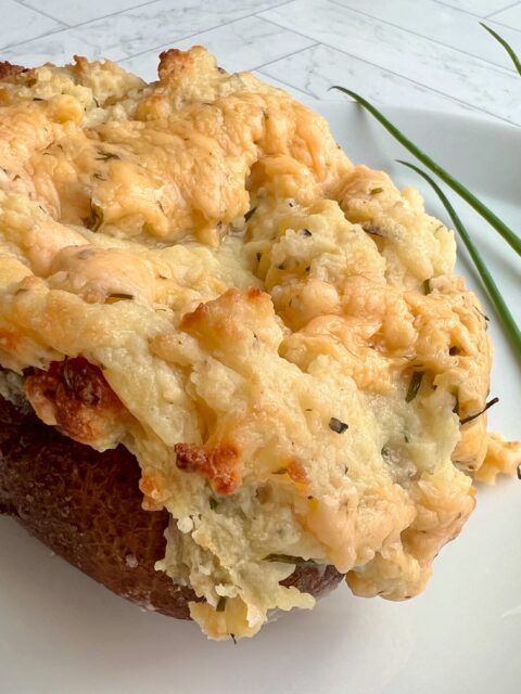 Picture of a chive twice baked potatoes with chives in the background