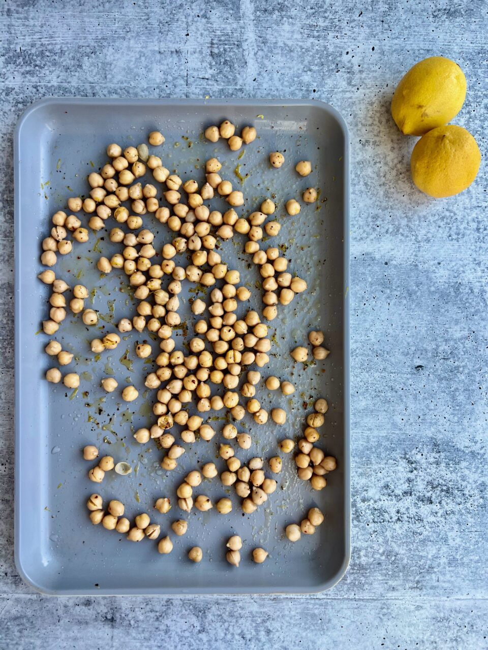 A cookie sheet with chickpeas and lemons